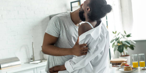 african american boyfriend kissing girlfriend neck at kitchen