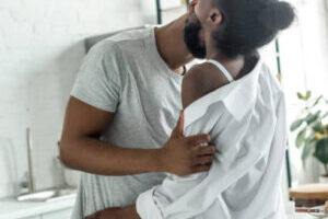 african american boyfriend kissing girlfriend neck at kitchen